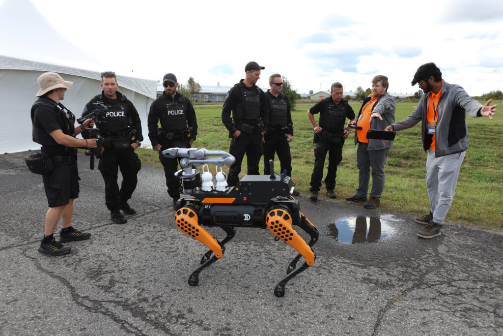 A group of people gather around a robot dog outside on an overcast day .